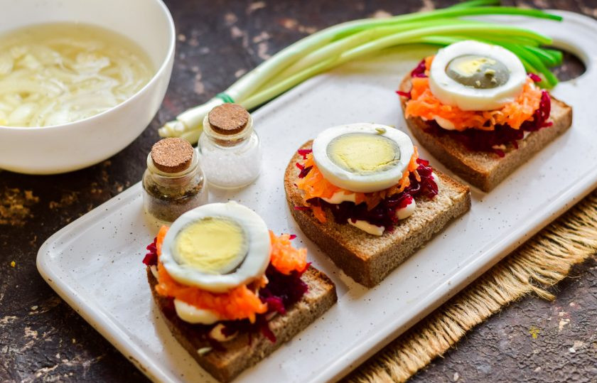 1. Этап. Бутерброды Сельдь под шубой: Куриное яйцо нарежьте небольшими кружочками и выложите поверх моркови.