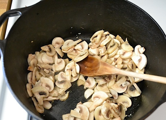 1. Этап. Перловка с шампиньонами: 2. После чеснока выложите в казан очищенные грибы, обжаривайте грибы до испарения жидкости.