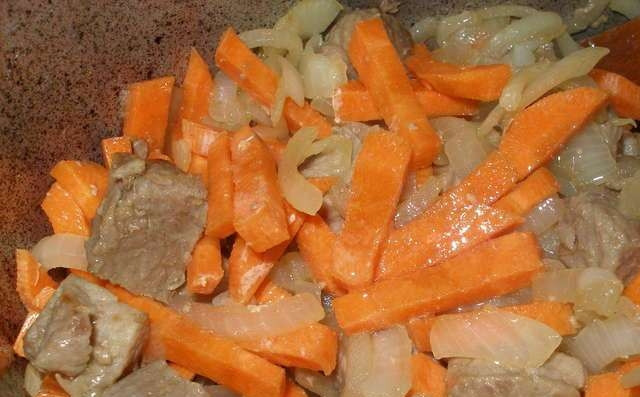 1. Этап. Плов с курагой: В казан наливаем немного масла и обжариваем свинину до золотистой корочки. Добавляем лук и морковь и тоже слегка обжариваем. Кладем в казан курагу, солим и добавляем специи и в течение 5 минут все вместе обжариваем.