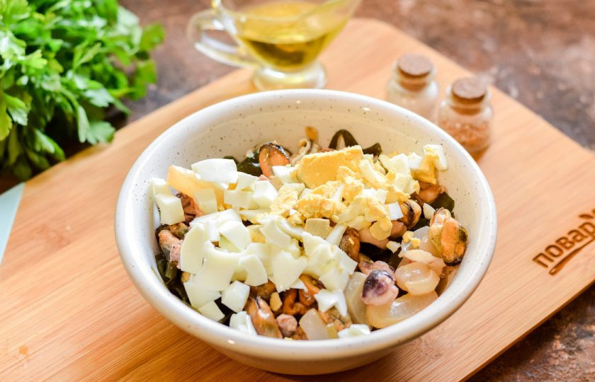 1. Этап. Салат из морской капусты и морского коктейля: Куриное яйцо отварите заранее 10 минут в подсоленной воде. Очистите и нарежьте яйцо небольшими кубиками.