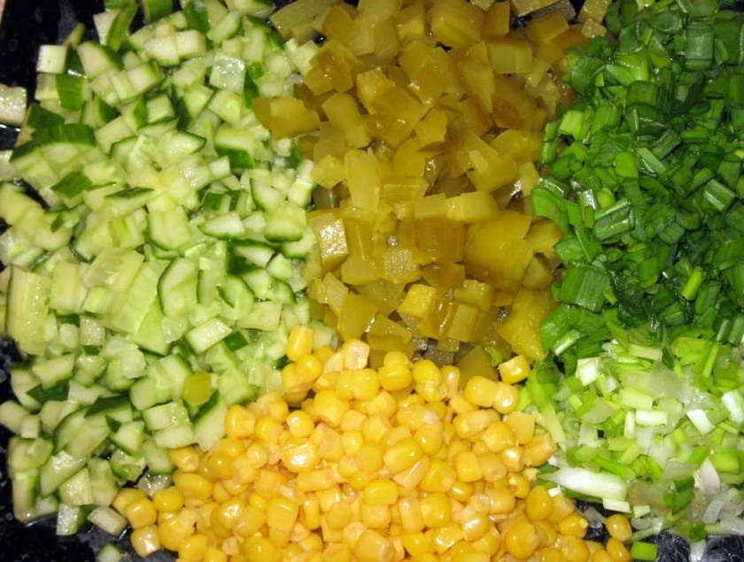 1. Этап. Салат Оливье с кукурузой: Измельчаем зеленый лук, кукурузу выкладываем в тарелку (жидкость сливаем). Осталось порезать кубиками соленые огурцы и свежий огурец.