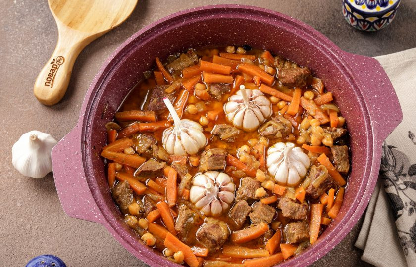 1. Этап. Плов с нутом и рисом: Снимите верхний слой шелухи с головок чеснока, оставляя их целыми и тщательно промойте. Содержимое казана перемешайте, разровняйте и выложите сверху подготовленный чеснок.