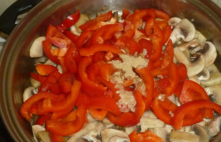 1. Этап. Курица с кешью и грибами: Добавьте перец. Пропустите через пресс чеснок. Влейте вино, добавьте имбирь. Перемешайте и готовьте под крышкой 3-4 минуты.