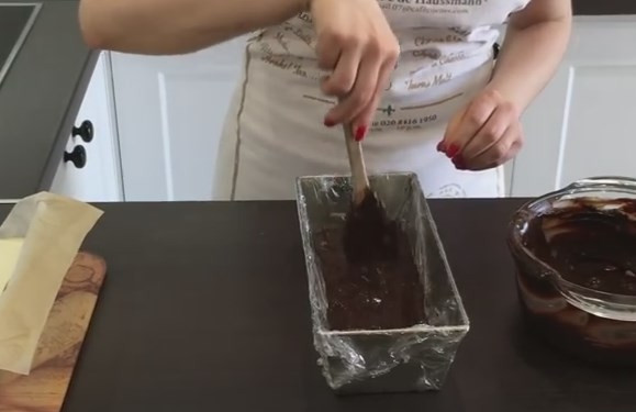 1. Этап. Домашние глазированные сырки: 8. Извлеките запеченный творог из формы и поставьте остывать. Форму со всех сторон оберните пищевой пленкой и вылейте в нее половину шоколадной помадки. Разровняйте.