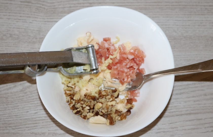 1. Этап. Чернослив фаршированный грецкими орехами: Выдавите чеснок через чесночницу.