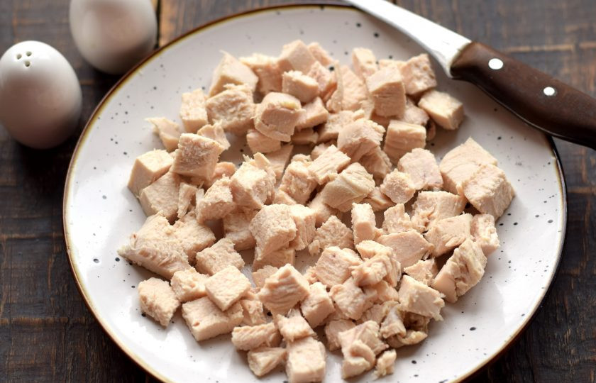 1. Этап. Салат с курицей, пекинской капустой и черносливом: Куриное филе заранее отварите в подсоленной воде до готовности. Примерное время варки составляет 15 минут после кипения жидкости. Отварное мясо полностью остудите, нарежьте на средние кубики и полоски.