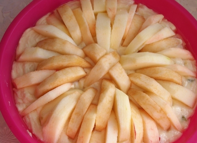 1. Этап. Яблочный пирог с творогом и цукатами: 7. Форму, в которой буду выпекать пирог, смазываю подсолнечным маслом. Выливаю в неё приготовленное тесто. Выкладываю кусочки яблок в форме солнышка, отправляю форму в разогретый до 180 градусов духовой шкаф на 50 минут.