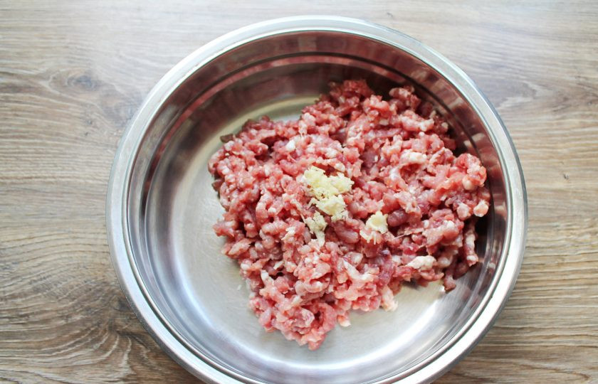 1. Этап. Домашняя колбаса на сковороде: Свинину вымойте, обсушите и порежьте на куски. Пропустите через мясорубку с крупной решеткой. Выложите фарш в миску, добавьте измельченный чеснок.