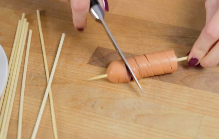 1. Этап. Торнадо-доги: 1. Для начала разрежьте соски на две части, если они у вас слишком длинные. Затем наденьте их на шпажки и с помощью ножа сделайте спиральный разрез по всей длинные сосиски, постепенно прокручивая ее.