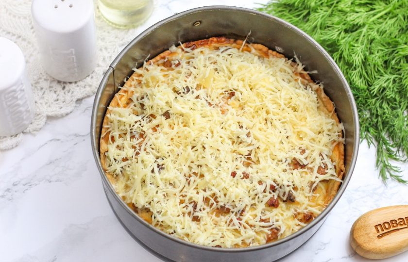 1. Этап. Пирог со свининой: Спустя указанное время натрите твердый сыр на терке с мелкими ячейками и присыпьте пирог сверху. Запеките еще 5 минут.