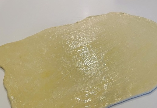 1. Этап. Мясные слоено-дрожжевые пирожки: Делим тесто на 2 части, каждую раскатываем в прямоугольник и смазываем растопленным сливочным маслом.