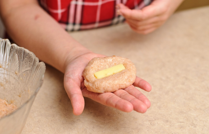 1. Этап. Куриные котлеты с плавленым сыром: 6. Сырок порежьте полосками. Смоченными в воде руками лепим продолговатый блинчик, в центр которого выкладываем приготовленный кусочек сыра.