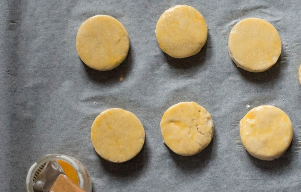 1. Этап. Булочки к завтраку: Выкладываем кружочки теста на противень, застеленный бумагой для выпечки. Смазываем их взбитым желтком.