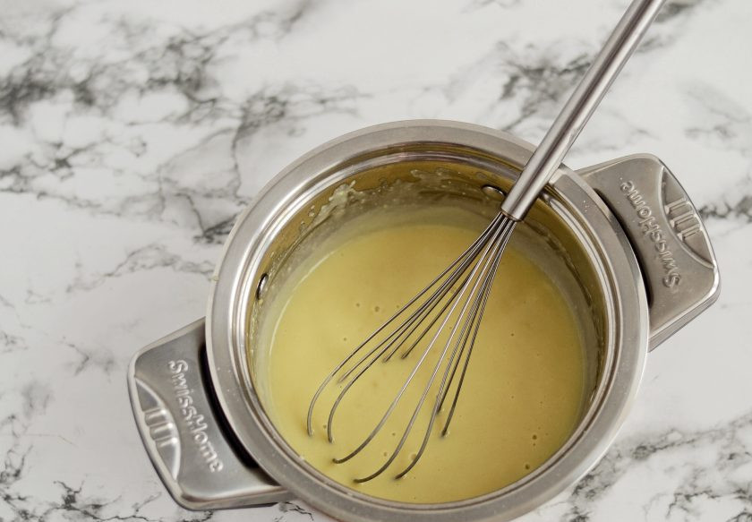 1. Этап. Запеканка с бататом: В кастрюле с толстым дном обжарьте на среднем огне муку до золотистого цвета. Добавьте растительный спред, перемешайте. Затем добавьте соль, пищевые дрожжи, сухой чеснок и сразу влейте соевое молоко. Мешайте до загустения соуса.