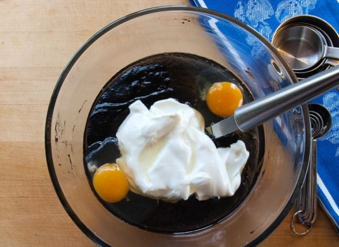 1. Этап. Американский шоколадный кекс: 3. Затем в полученную шоколадную массу добавьте сметану, ванилин и яйца. Всё тщательно перемешайте. Потом добавьте сухую смесь. Замешайте тесто.