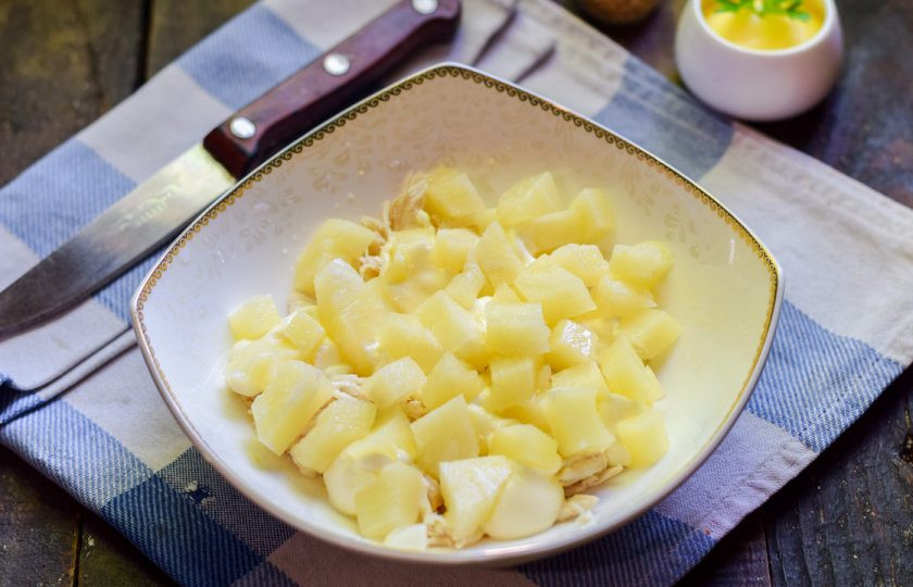 1. Этап. Салат Царский с ананасами: Кольца ананасов нарежьте небольшими кубиками, выложите поверх курицы. Это будет второй слой.