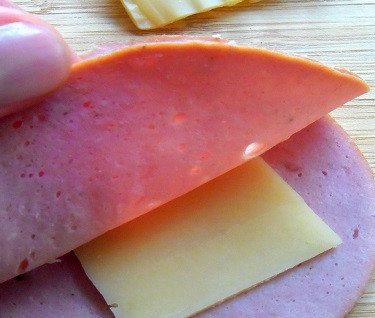 1. Этап. Колбаса в кляре с сыром: 2. Возьмите два кусочка колбасы, между ними вложите кусочек сыра.