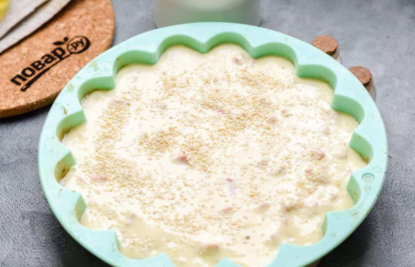 1. Этап. Быстрый пирог с колбасой: Переложите тесто в форму, посыпьте кунжутом и выпекайте в духовке при температуре 180 градусов в течение 35-40 минут.