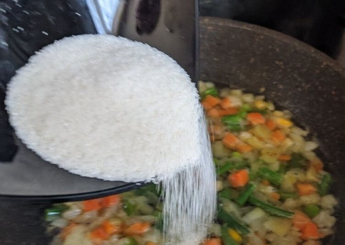 1. Этап. Кальмары, фаршированные рисовой полентой и овощами: Тонкой струйкой всыпаем рисовую поленту в кипящую воду (с овощами). Перемешиваем. Готовим около 10 минут до загустения поленты, помешивая, чтобы не пригорела.