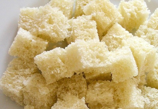 1. Этап. Салат Цезарь с семгой: Батон нарежьте кубиками, полейте получившимся чесночным маслом, перемешайте, выложите на противень.