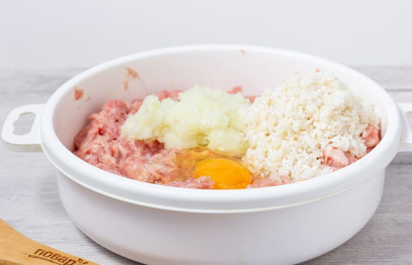 1. Этап. Ежики как в детском саду: В фарш добавьте лук, пробитый блендером, яйцо и полуготовый рис. Тщательно перемешайте и посолите по вкусу.
