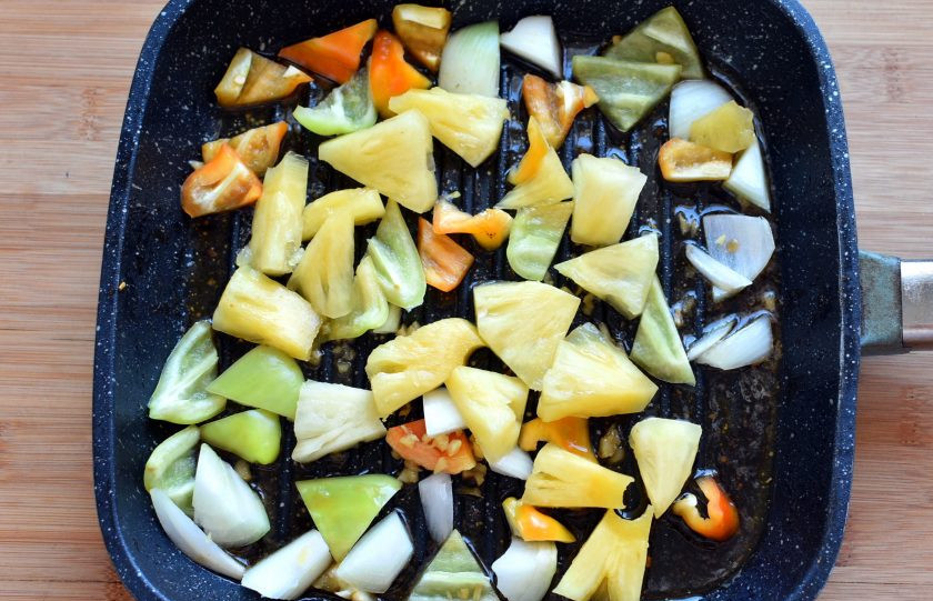 1. Этап. Свиная вырезка по-азиатски с кисло-сладким соусом: В сковороду выложите нарезанные лепестками лук и перцы, добавьте кусочки ананаса и рубленный имбирь. Обжарьте при помешивании до легкой корочки.