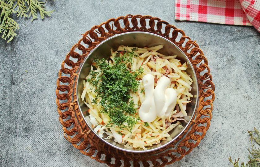 1. Этап. Салат с огурцом, кальмаром и яблоком: Зелень мелко порежьте и добавьте в миску с кальмарами, яблоком и огурцом. Салат посолите, заправьте майонезом, перемешайте и подавайте.