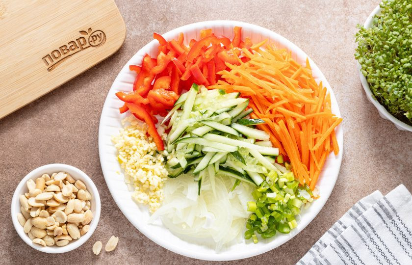 1. Этап. Закуска с древесными грибами и арахисом: Подготовьте овощи. Репчатый лук нарежьте полукольцами, болгарский перец и огурец брусочками, а морковь очистите от кожуры и натрите на терке для моркови по-корейский. Чеснок мелко порубите, а зеленый лук мелко нарежьте.