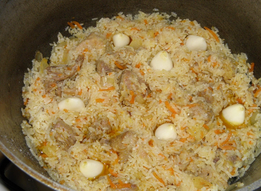 1. Этап. Плов: 9. Добавьте рис, перемешайте, как бы обжаривая рис в жиру. Вставьте внутрь чеснок.