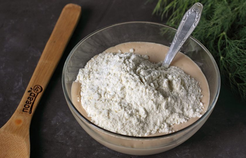 1. Этап. Сырные лепешки за 15 минут: В глубокой миске соедините кефир, соль, сахар и соду. Перемешайте и оставьте на 5 минут. Затем добавьте стакан муки.