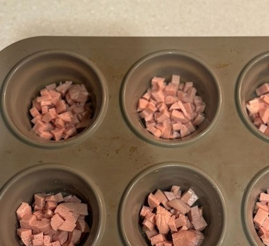 1. Этап. Закусочные маффины из яиц: Сосиски мелко нарезать, выложить в формочки