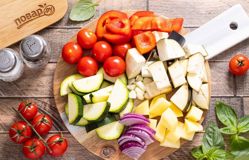 1. Этап. Рататуй с картошкой на сковороде: Картофель очистите от кожуры, нарежьте кубиками. Баклажаны и красный перец нарежьте ломтиками среднего размера, а репчатый лук полукольцами. Цукини нарежьте толстыми кружочками или четвертинками. Чеснок очистите и порежьте пластинами. Помидоры черри оставьте целыми, а если используете обычные томаты, то нарежьте их кубиками.