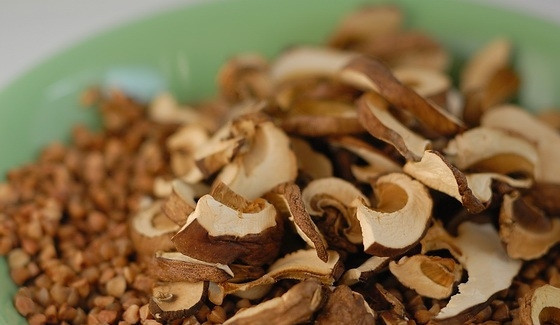 1. Этап. Гречка с сушеными грибами: Гречку переберите и промойте. Грибы замочите в воде на 20 минут. Переложите ингредиенты в жаропрочный горшок.