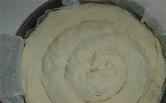 1. Этап. Сырная улитка: Форму для выпекания нужно выложить пергаментной бумагой и смазать ее сливочным маслом. Из первой трубочки нужно сделать небольшую улитку, это будет середина вашей булочки. Улитку положите в середину формы. Дальше выкладываем улитку, оборачивая серединку получившейся 