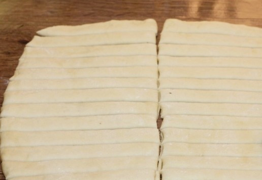 1. Этап. Морские узелки с чесночным маслом: 9. Раскатайте тесто в толстый пласт, разрежьте на 2 части. По желанию, одну часть можно смазать томатным кетчупом.