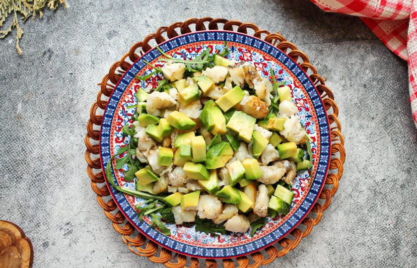 1. Этап. Салат с треской и авокадо: Авокадо разрежьте вдоль на две половинки, разделите и удалите ядрышко. Удалите кожуру и порежьте таким же кубиком как свежий огурец. Разложите авокадо поверх салата. Заправьте салат заправкой и подавайте к столу.