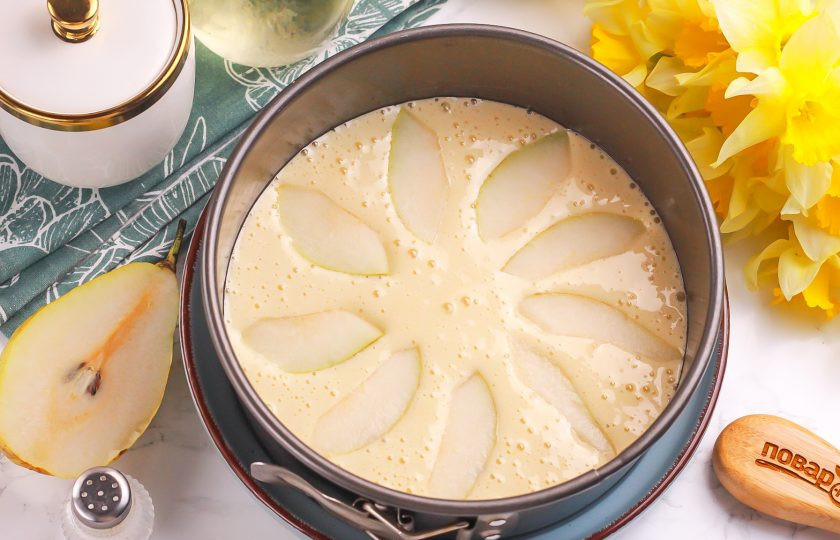 1. Этап. Шарлотка с грушами в аэрогриле: Грушу промойте в воде и обсушите бумажной салфеткой. Разрежьте на четыре части и вырежьте семенные блоки. Нарежьте мякоть ломтиками и выложите сверху на тесто.