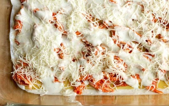 1. Этап. Куриная лазанья: 11. Натрите сыр на терке, добавьте часть поверх соуса.