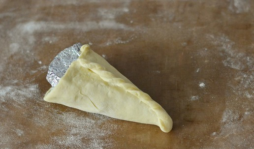 1. Этап. Коно пицца: Обильно натрите его мукой и оберните тесто вокруг конуса из фольги. Защипайте края и тщательно скрепите их 