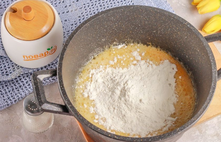 1. Этап. Медовик с вареной сгущенкой и сметаной: Всыпьте треть пшеничной муки и замесите вязкое тесто. Это делается для того, чтобы при добавлении яиц, они не свернулись в горячей массе.