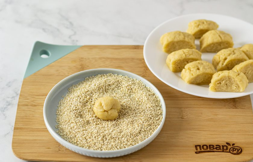1. Этап. Кунжутное печенье: Скатайте тесто в колбаску и разделите на 10-12 частей. Из каждой части скатайте шарик и обваляйте его в кунжуте.