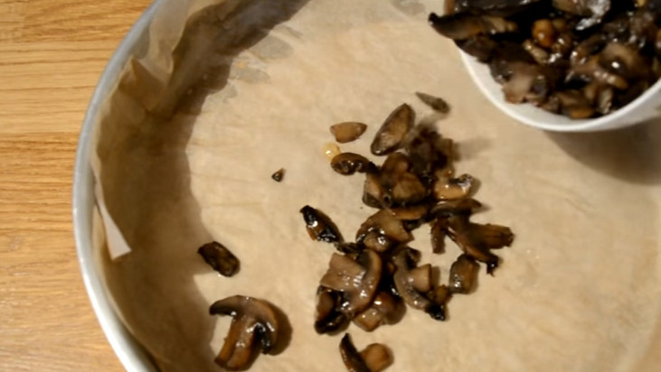 1. Этап. Пирог-перевертыш с мясом и грибами: 5. Форму застилаем пергаментом и смазываем растительным маслом, на дно кладем грибы. Твердый сыр измельчаем на крупной терке и добавляем к грибам.