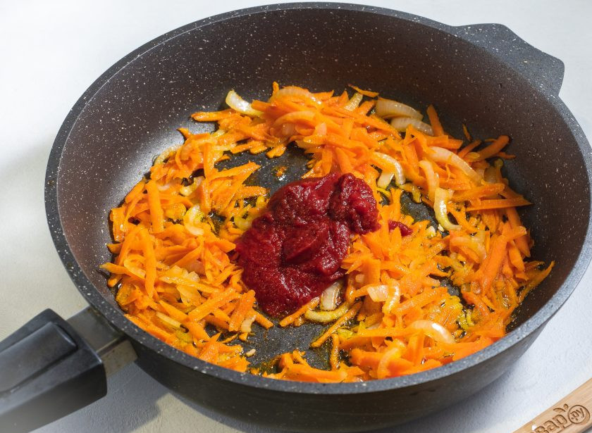 1. Этап. Рис с мясом и капустой в сковороде: На сковороде в растительном масле обжарьте до прозрачности лук, нарезанный полукольцами. Затем добавьте натертую на крупной терке морковь. Жарьте 2-3 минуты и добавляйте томатную пасту.