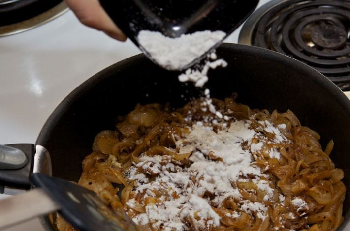 1. Этап. Классический луковый суп: 2. Когда лук пропассируется в течение 10 минут, добавьте щепотку сахара, чтобы лук стал коричневым. Продолжайте карамелизировать лук в течение 30 минут. После добавьте пюре чеснока, муку и обжарьте все вместе 5 минут.