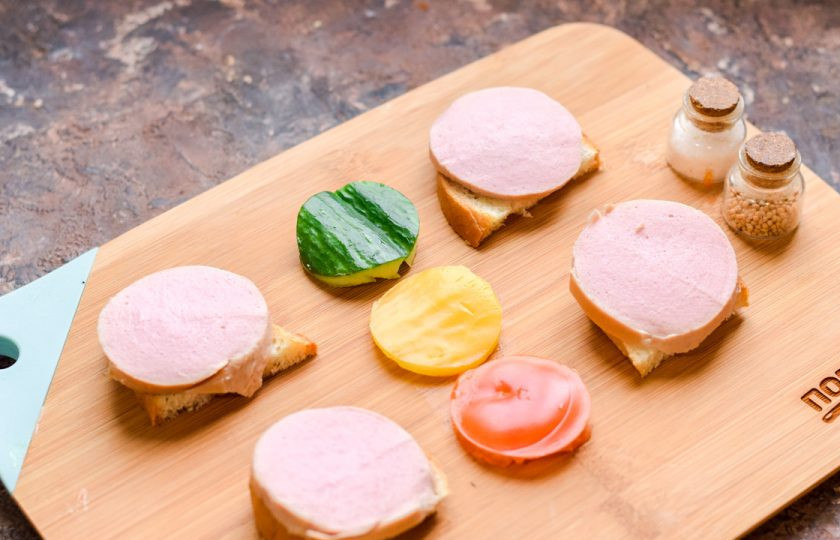 1. Этап. Бутерброды Дорожные знаки: Вареную колбасу нарежьте небольшими кружочками, выложите поверх хлеба.