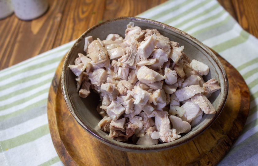 1. Этап. Салат с курицей, грибами и грецким орехом: С отварных куриных бедер отделите кости и снимите кожу. Мякоть нарежьте небольшими кусочками.