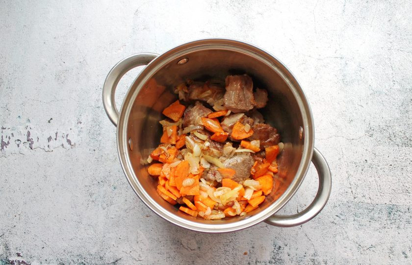 1. Этап. Томленая пашина: Переложите овощи к мясу, посолите, добавьте черный перец и влейте воду, чтобы она только покрывала мясо.