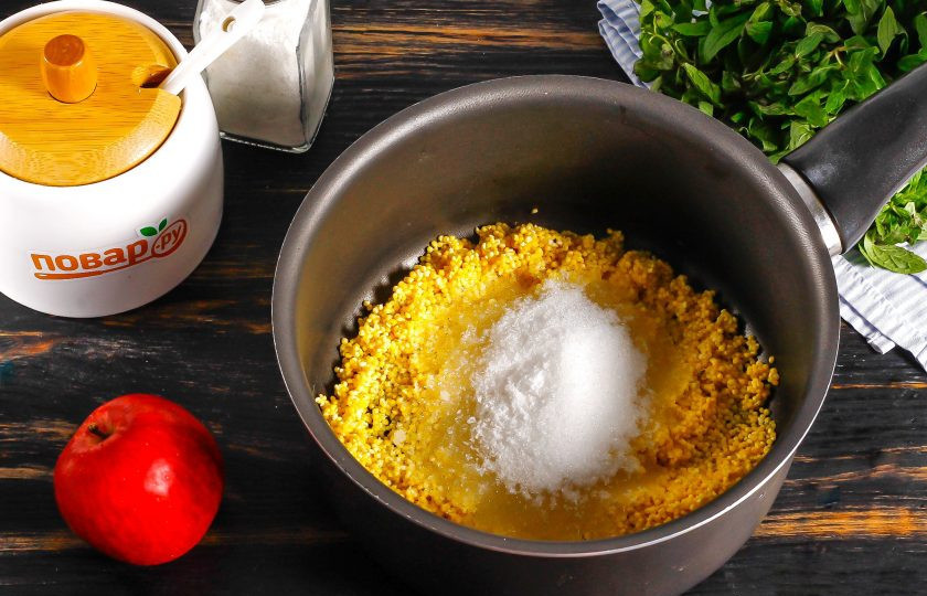 1. Этап. Янтарная каша из пшена с яблоками: Промытую крупу пересыпьте в казан или ковш, кастрюлю с антипригарным дном. Добавьте соль и сахар. Влейте теплую воду и отварите примерно 10 минут, снимая образующуюся пену, ее будет много.