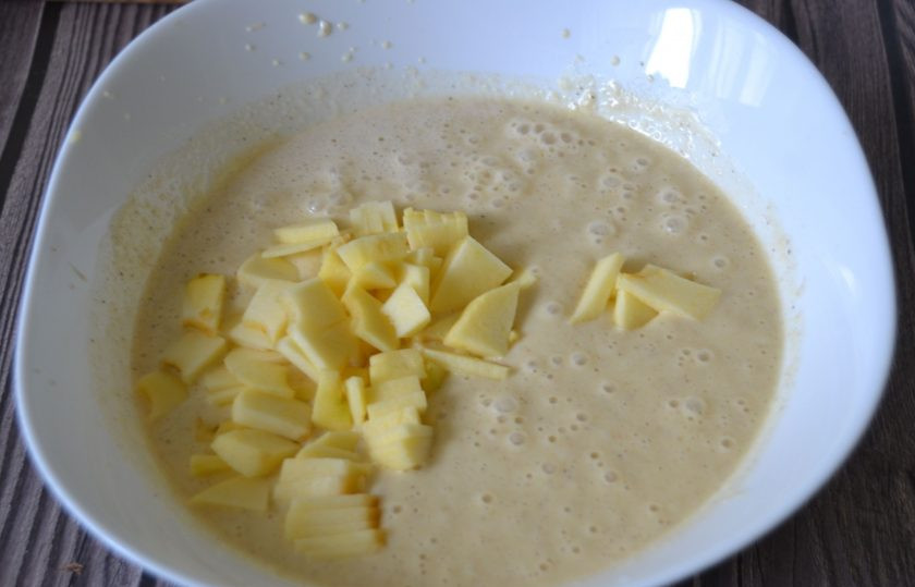 1. Этап. Манник с яблоками на сметане: Всыпьте мелко нарезанное яблоко в тесто, размешайте.