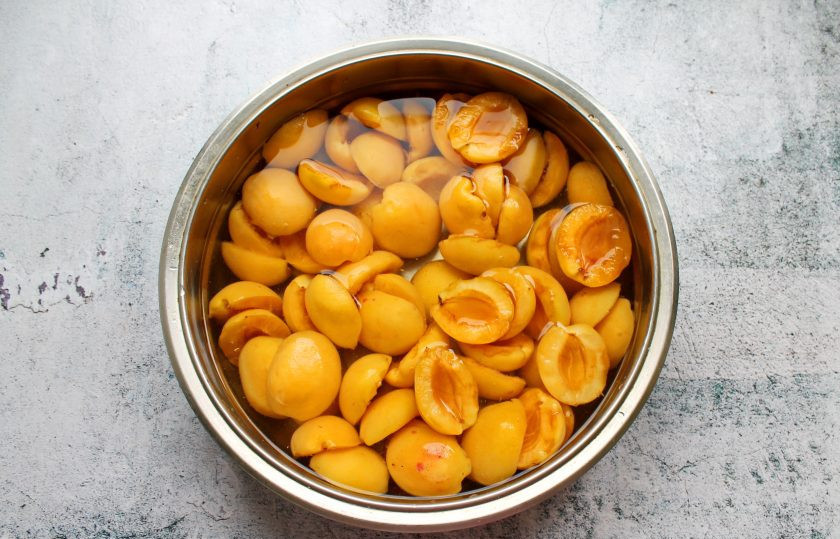 1. Этап. Сушка абрикосов в электросушилке: Абрикосы переберите, вымойте, разделите, пополам удаляя косточки, выложите в миску. В холодной воде разведите лимонную кислоту и залейте половинки абрикосов, оставьте на 10 минут. Затем откиньте их на сито и дайте воде полностью стечь.